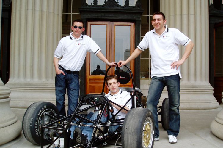 Jim Cuseo SM '05, Richard James ’04, SM ’06, and Joseph Audette ’05 with the MIT Motorsports formula-one style racecar outside the doors of Building 10