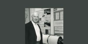 A black and white photo of Lynn Sykes standing by a round machine